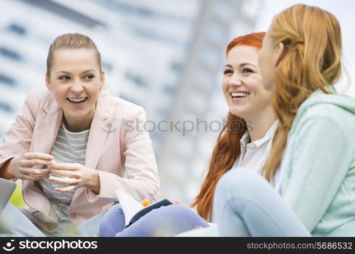 Happy young female college friends studying outdoors