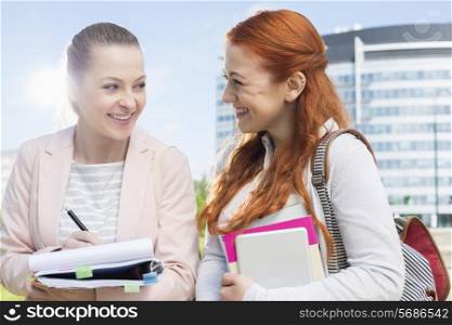 Happy young female college students studying outdoors