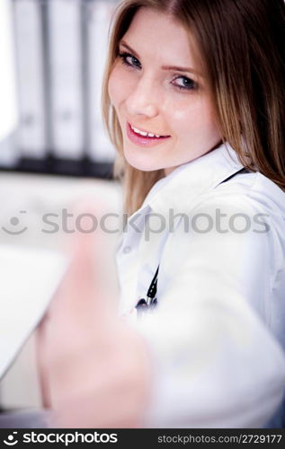 Happy young female doctor showing thumbs up sign