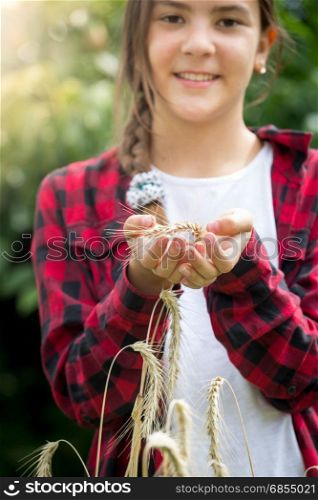 Happy young female farmer posing in wheat field at sunny day