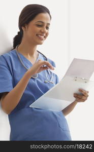 Happy young female surgeon reading notes on clip board