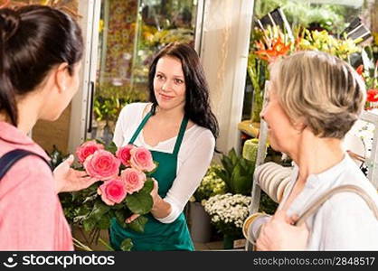 Happy young florist woman showing roses flowers customers shop