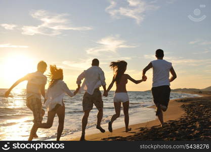 happy young friends group have fun and celebrate while jumping and running on the beach at the sunset