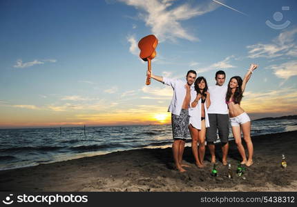 happy young friends group have fun and celebrate while jumping and running on the beach at the sunset