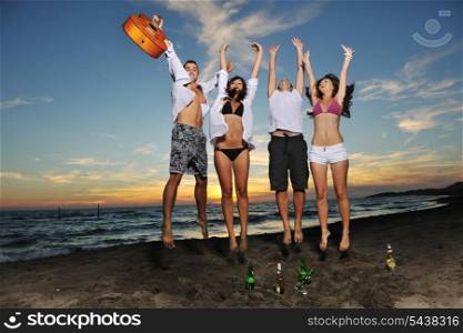 happy young friends group have fun and celebrate while jumping and running on the beach at the sunset