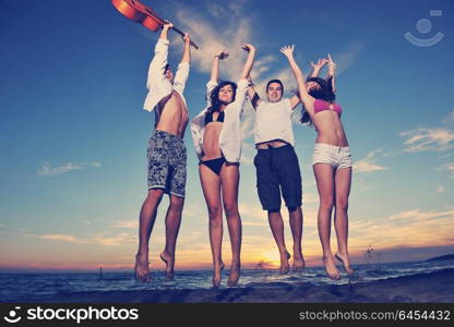 happy young friends group have fun and celebrate while jumping and running on the beach at the sunset