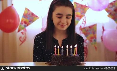 Happy young girl blowing out candles on a birthday cake.