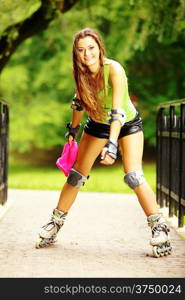 Happy young girl enjoying roller skating rollerblading on inline skates sport in park. Woman in outdoor activities