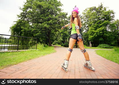 Happy young girl enjoying roller skating rollerblading on inline skates sport in park. Woman in outdoor activities