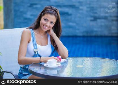 Happy young girl in summer outdoor cafe with coffee and cake. Girl in outdoor cafe