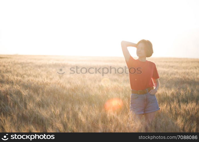 happy young girl joys at the wheat field at the evening time. sunset and atmospheric mood