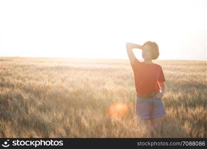 happy young girl joys at the wheat field at the evening time. sunset and atmospheric mood
