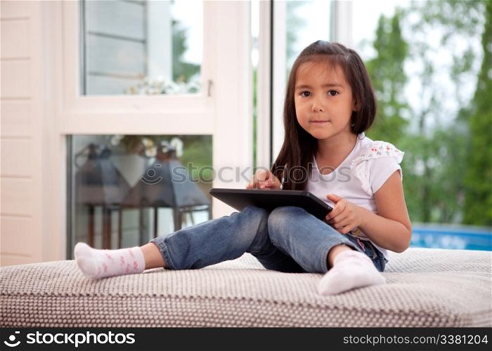 Happy young girl looking at the camera holding a digital tablet