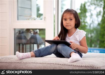 Happy young girl looking at the camera holding a digital tablet