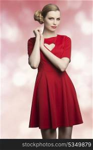 happy young girl with blonde elegant hair-style and pretty make-up wearing red dress with heart shaped neckline. Romantic style