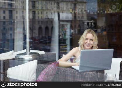 Happy young girl with laptop in restaurant