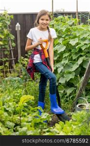 Happy young girl working at garden with shovel
