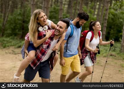 Happy young group of people hiking together through the fores