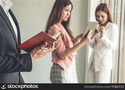 Happy young handsome businessman reading book and working in office with colleagues and friend at workplace. Corporate business people group.