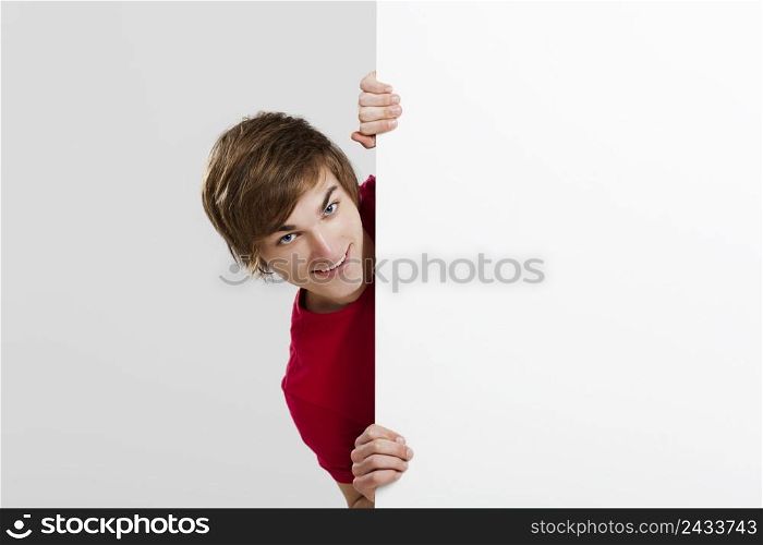 Happy young hiding and looking behind a blank white card