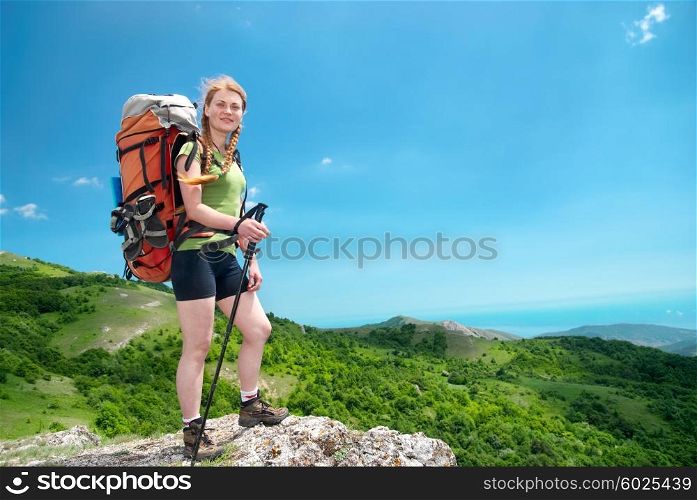 Happy young hiking woman with backpack on the mountain