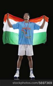 Happy young hockey medalist with Indian flag standing against black background