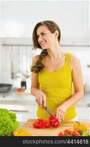 Happy young housewife cutting fresh vegetable salad