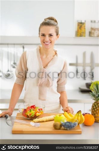 Happy young housewife cutting fruits in kitchen