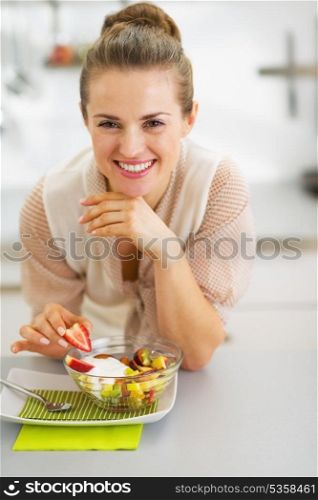 Happy young housewife decorating fruits salad