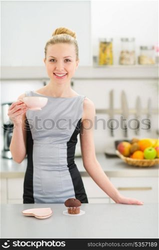 Happy young housewife drinking coffee with chocolate muffin