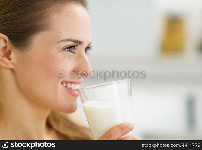 Happy young housewife drinking milk