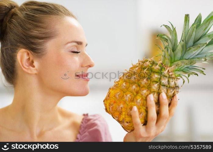 Happy young housewife enjoying fresh pineapple