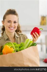 Happy young housewife examines purchases after shopping in kitchen