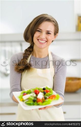 Happy young housewife giving fresh salad