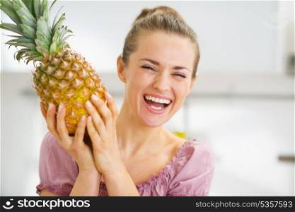 Happy young housewife holding fresh pineapple