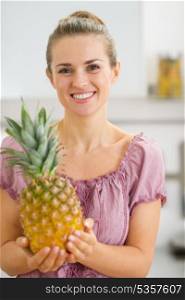 Happy young housewife holding fresh pineapple