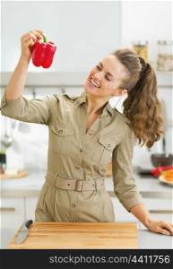 Happy young housewife holding red bell pepper