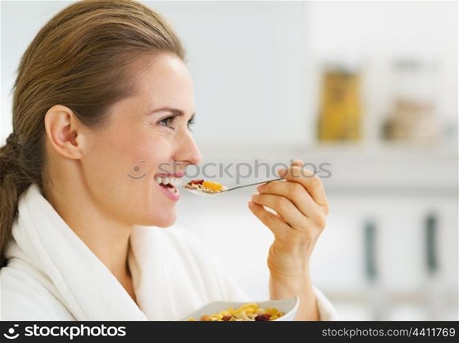 Happy young housewife in bathrobe having healthy breakfast