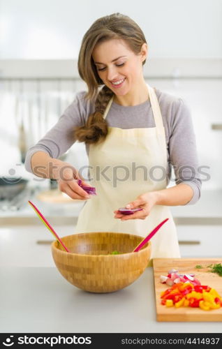 Happy young housewife mixing vegetable salad