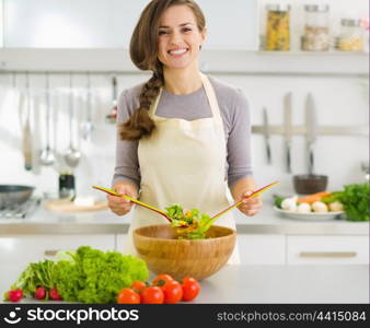 Happy young housewife mixing vegetable salad