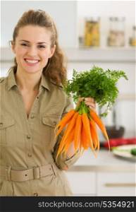 Happy young housewife showing fresh carrots