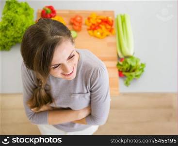 Happy young housewife standing in modern kitchen