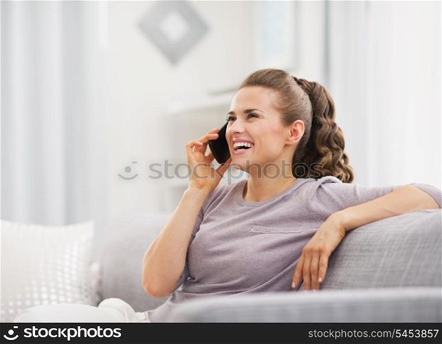 Happy young housewife talking cell phone in living room