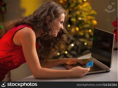 Happy young housewife with credit card making online christmas purchases