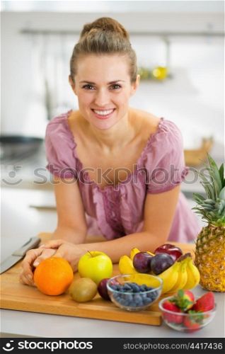 Happy young housewife with fruits on cutting board