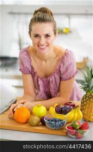 Happy young housewife with fruits on cutting board