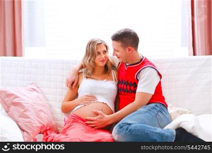 Happy young husband holding his pregnant wifes belly&#xA;