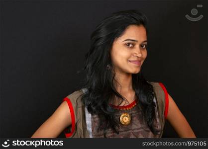 Happy young Indian woman smiling against black background, Pune, India