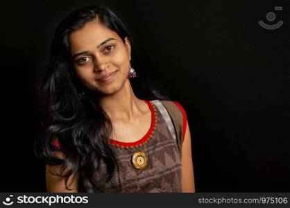 Happy young Indian woman smiling against black background, Pune, India