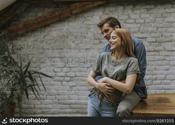 Happy young lovely couple in the rustic kitchen hugging each other